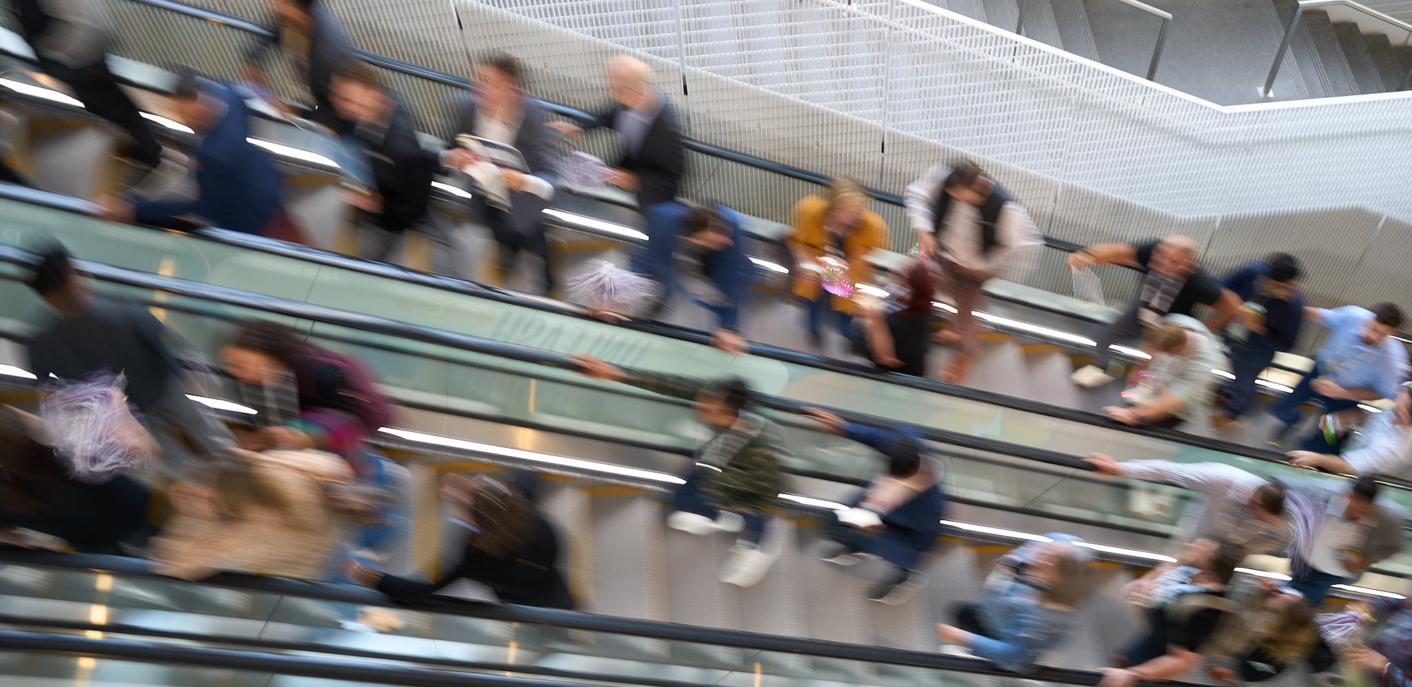 Blurry image of people riding up an escalator